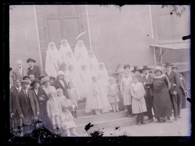 Communiantes et familles sur le perron d'une habitation.