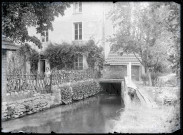 Jeune fille s'appuyant à une barrière séparant une habitation d'un cours d'eau.