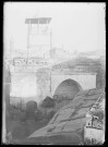 Vue d'une cour sous les arcades avec à l'arrière-plan des minarets.