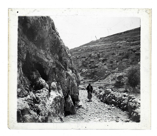 Enfant sur un sentier menant à un village à flanc de montagne.