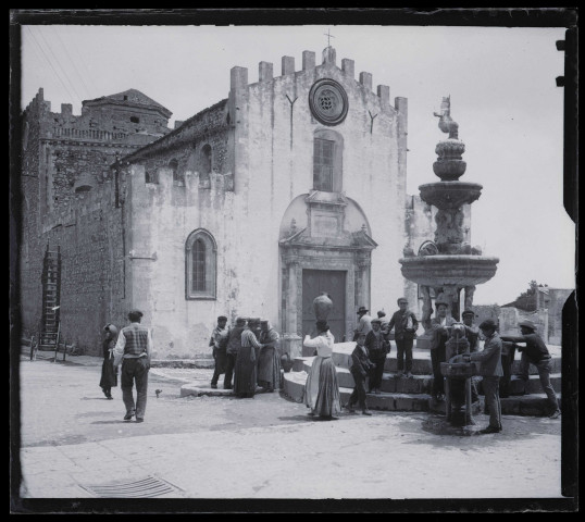 Villageois à la fontaine sur la place d'une église sicilienne.