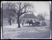 Hommes et leur cheval de trait au travail devant un bâtiment le 21 mars 1899.