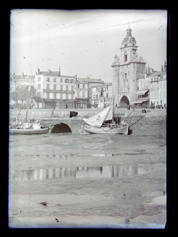 Porte de la Grosse-Horloge et bateaux de pêche dans le port à marée basse à la Rochelle (Charente-Maritime).