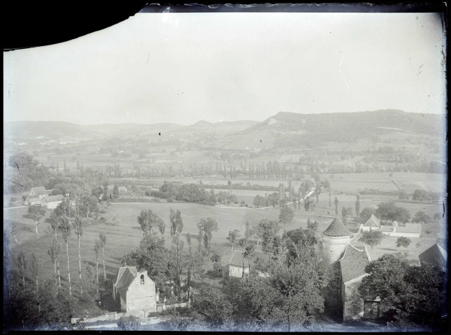 Vue sur une vallée avec un château, une chapelle et un ancien cimetière.
