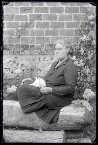 Rachel (Bretocq) assise avec un lapin sur les genoux dans le jardin.