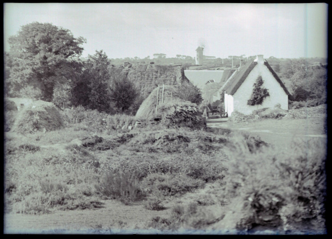 Maisons bretonnes et meules de foin, au loin un moulin.
