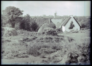 Maisons bretonnes et meules de foin, au loin un moulin.