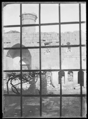 Remparts de la citadelle d'Alep (Syrie) vus à travers une grille (rajoutée par le photographe en appliquant de la gouache sur la plaque de verre).