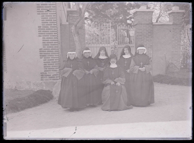 Religieuses devant la grille d'un bâtiment.