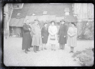 Hommes, femmes et prêtre posant dans la cour d'une habitation.