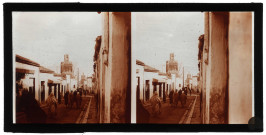 Bédouins dans les ruelles d'une ville d'Algérie, à l'arrière plan des minarets.