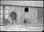 Jeunes enfants et leur âne dans une cour de ferme normande.