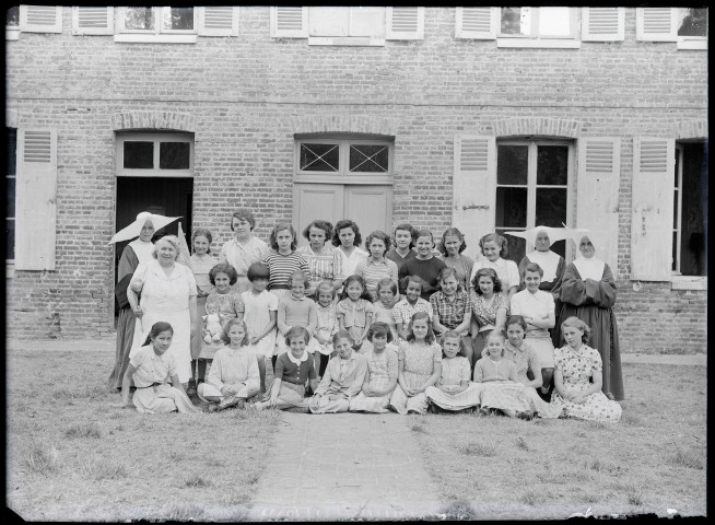 Groupe de jeunes filles encadrées de sœurs à cornettes, probablement une école catholique.