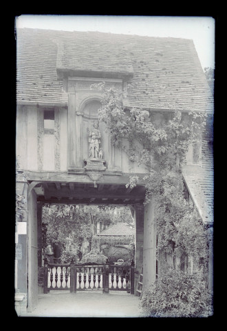 Porche sous arcade d'un manoir à pans de bois avec statue de Saint-Roch, probablement un hôtel.
