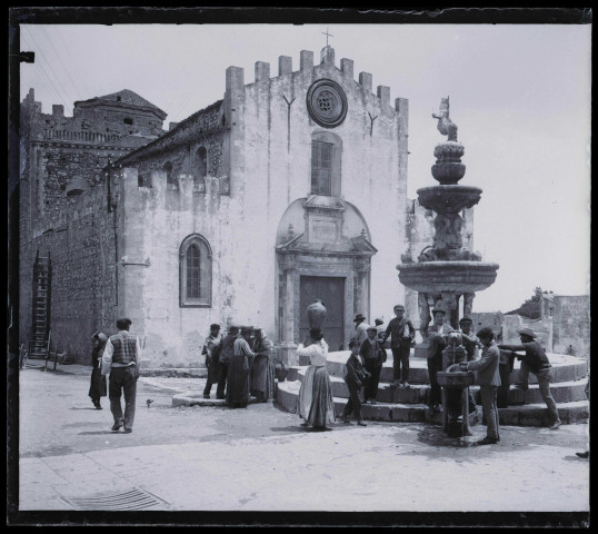 Villageois à la fontaine sur la place d'une église sicilienne.
