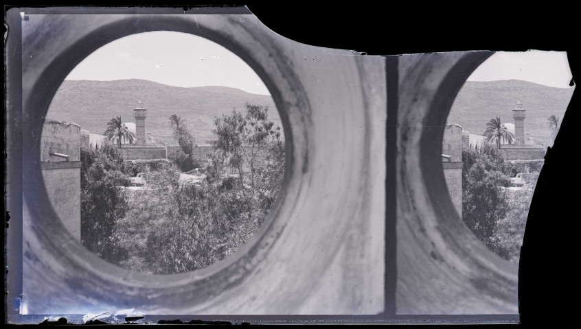 Vue d'une ville et de son minaret à travers un œil de bœuf.