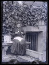 Femme à l'ouvrage sur un banc en pierre.