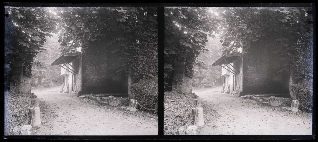 Bâtiment en pierre et briquettes rouges et lavoir dans la campagne.