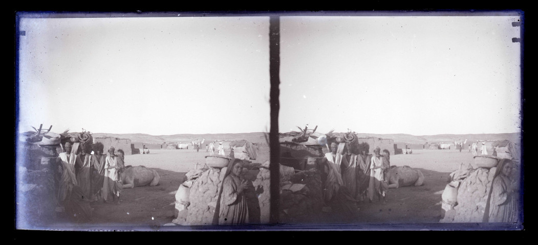 Paysans et leurs montures devant une habitation en terre.