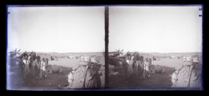 Paysans et leurs montures devant une habitation en terre.