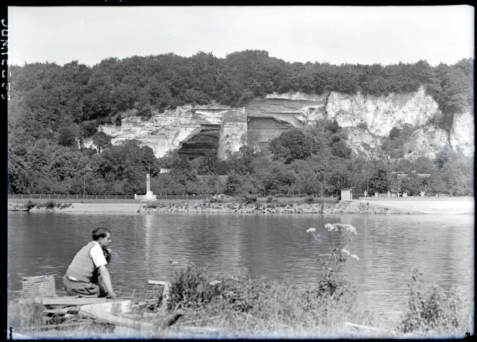 Jeune homme assis sur la rive de la Seine aux environs des ruines et vestiges de l'abbaye de Jumièges (Seine-Maritime).
