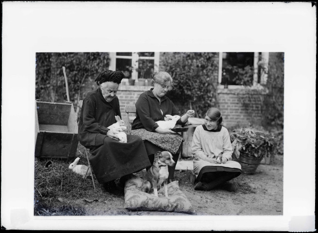 Femmes de la famille Bretocq dans le jardin avec des lapins et le chien "Milou".