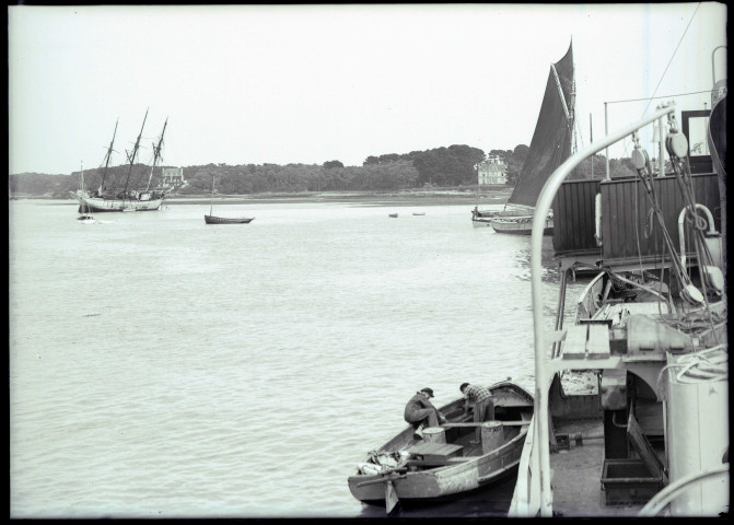 Marins occupés à bord d'une barque, chaloupes et voiliers dans une baie bretonne.