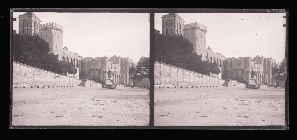 Esplanade avec statue au pied de remparts et de fortifications.