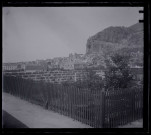 Petit potager en terrasse et vue d'un village au pied des montagnes.