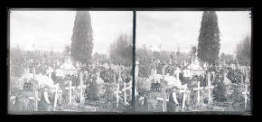 Cortège et corbillard dans un cimetière.