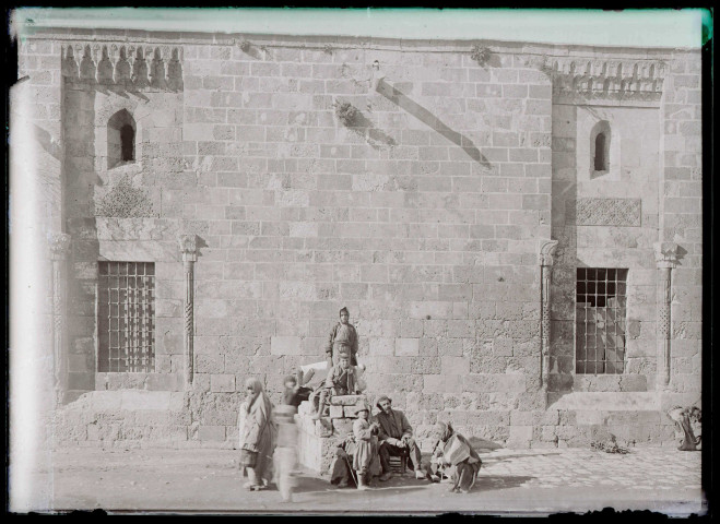 Vue d'un mausolée et d'un minaret à travers des remparts.