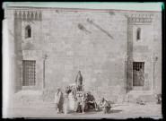 Vue d'un mausolée et d'un minaret à travers des remparts.