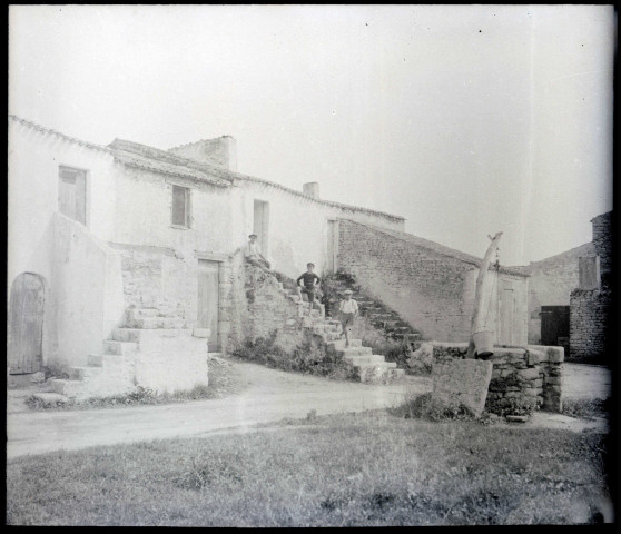 Jeunes garçons sur un escalier de pierre devant des habitations de campagne.