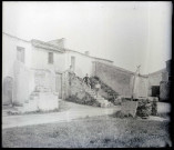 Jeunes garçons sur un escalier de pierre devant des habitations de campagne.
