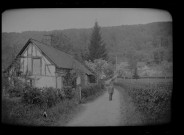 Portrait d'un homme sur une route bordée par une chaumière.