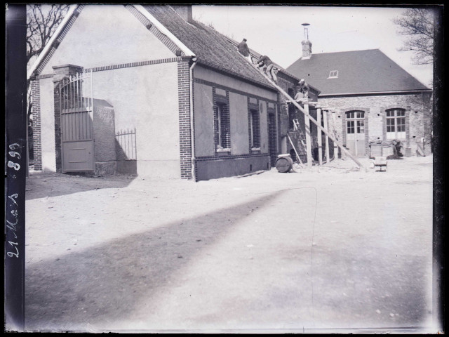 Couvreurs au travail sur le toit d'une habitation le 21 mars 1899.
