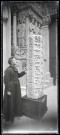 L'abbé Bretocq posant devant un fût de colonne octogonale en pierre portant les signes du zodiaques dans l'église abbatiale de Souvigny (Allier).