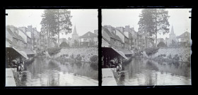 Femmes au lavoir dans une rivière traversant un village.