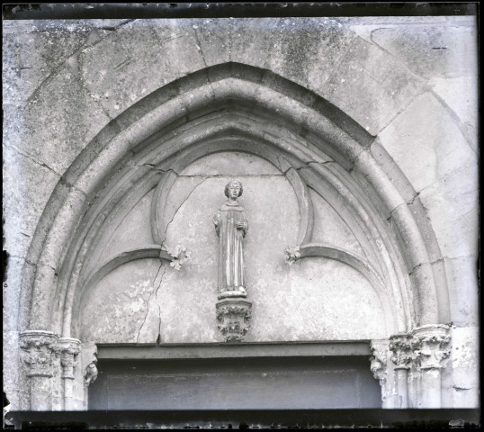Statue en pierre de Saint-Damien au tympan de la porte Sud de l'église Notre-Dame d'Écouis (Eure).