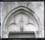 Statue en pierre de Saint-Damien au tympan de la porte Sud de l'église Notre-Dame d'Écouis (Eure).