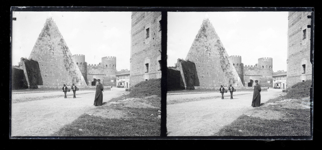 Prêtre posant devant la porte et les fortifications de ville italienne.
