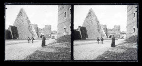 Prêtre posant devant la porte et les fortifications de ville italienne.