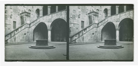 Cour intérieure ornementée avec balcon, puits et statues.