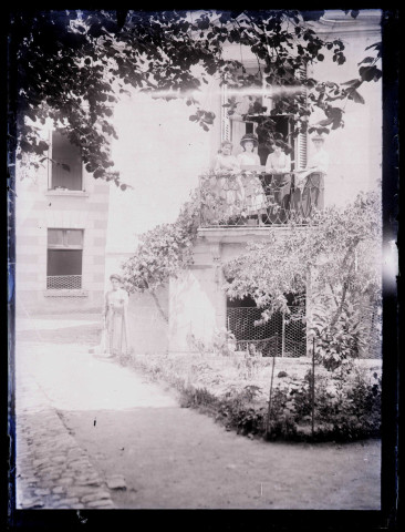 Femmes au balcon et au pied d'une habitation.