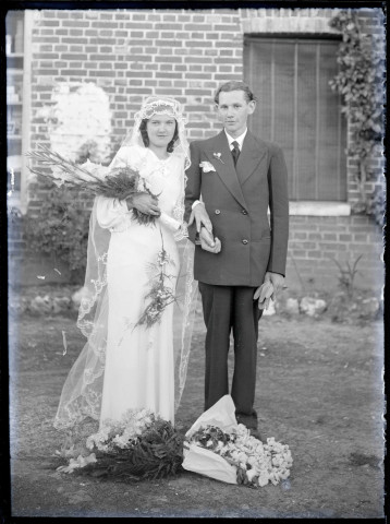 Portrait d'un couple de jeunes mariés devant l'épicerie de la famille Duramé à Rosay-sur-Lieure (Eure).
