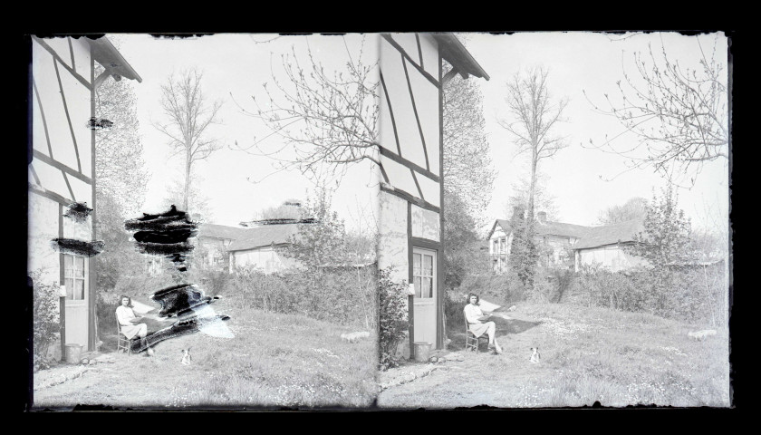 Jeune femme assise sur une chaise et lisant un livre devant sa maison dans la campagne normande.