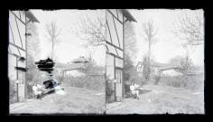 Jeune femme assise sur une chaise et lisant un livre devant sa maison dans la campagne normande.