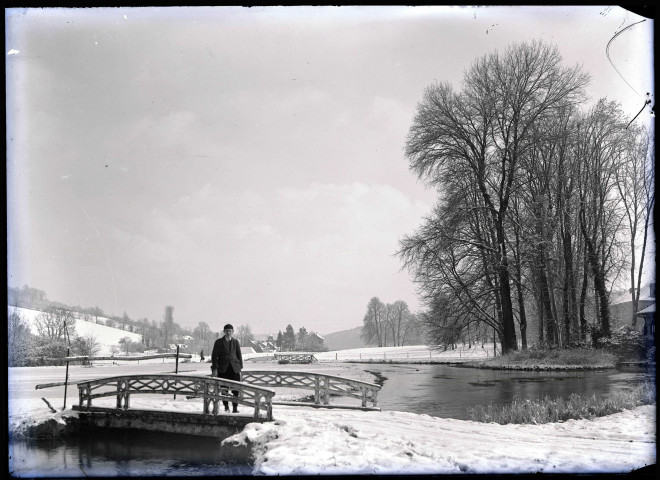 Enfant sur un pont dans la campagne normande enneigée.