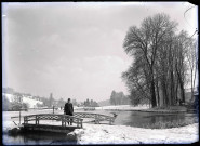 Enfant sur un pont dans la campagne normande enneigée.