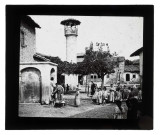 Enfants à la fontaine sur une place avec un minaret.